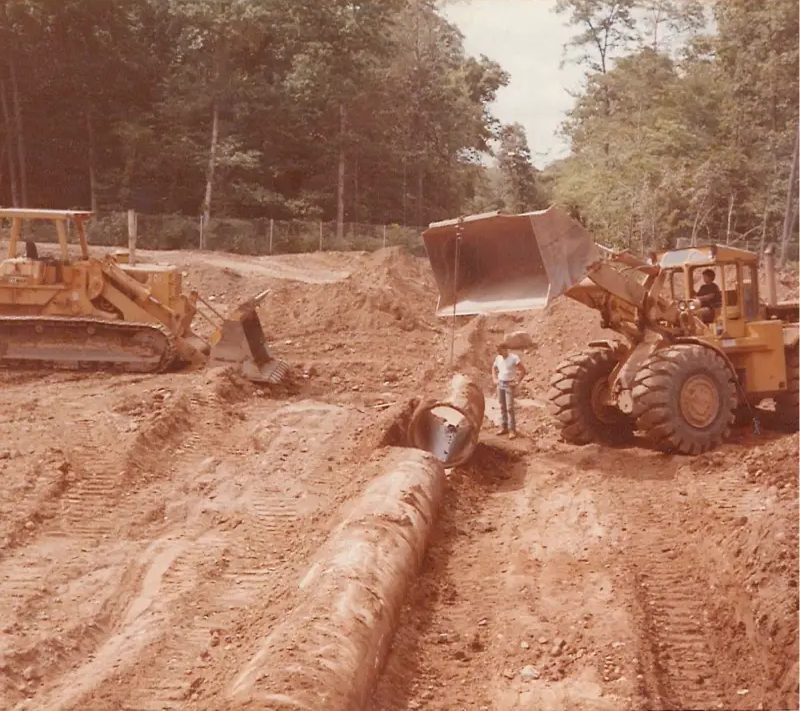 Loaders and a scraper working a graded earthwork pad.