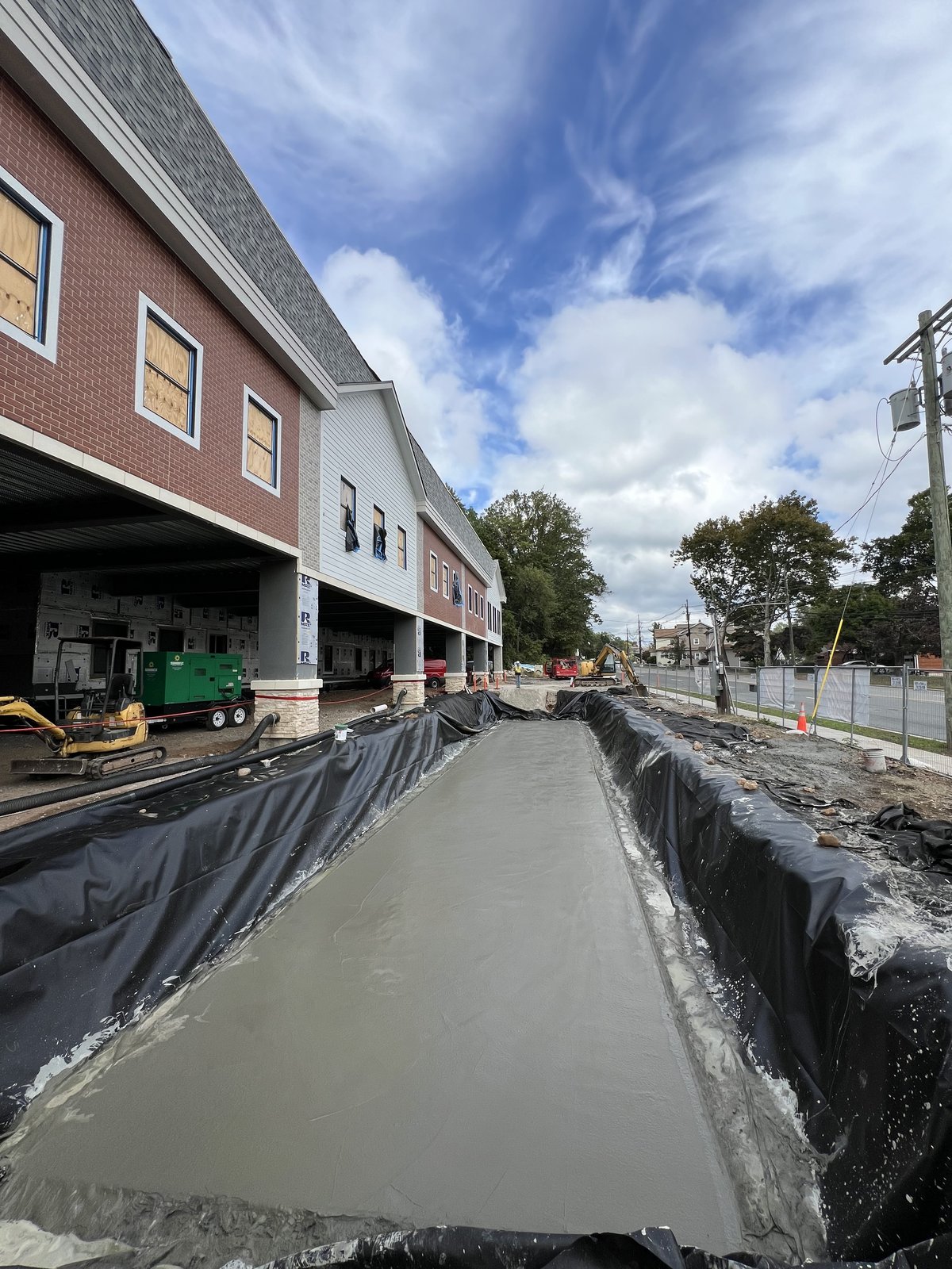 Concrete sidewalk pour viewed down the length of the Trojan Storage facade.